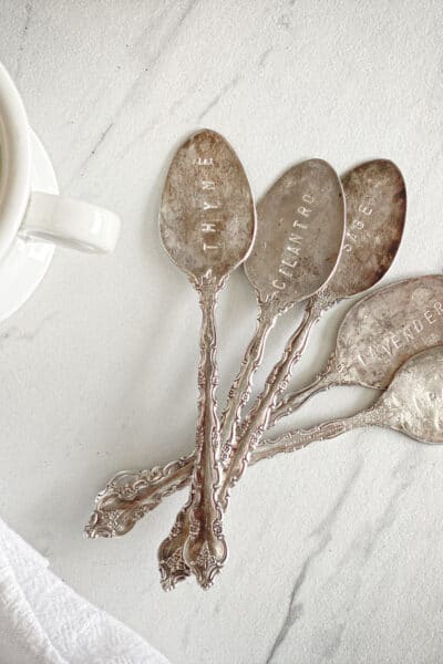 stamped antique spoons next to ironstone mug, flour sack towel and marble