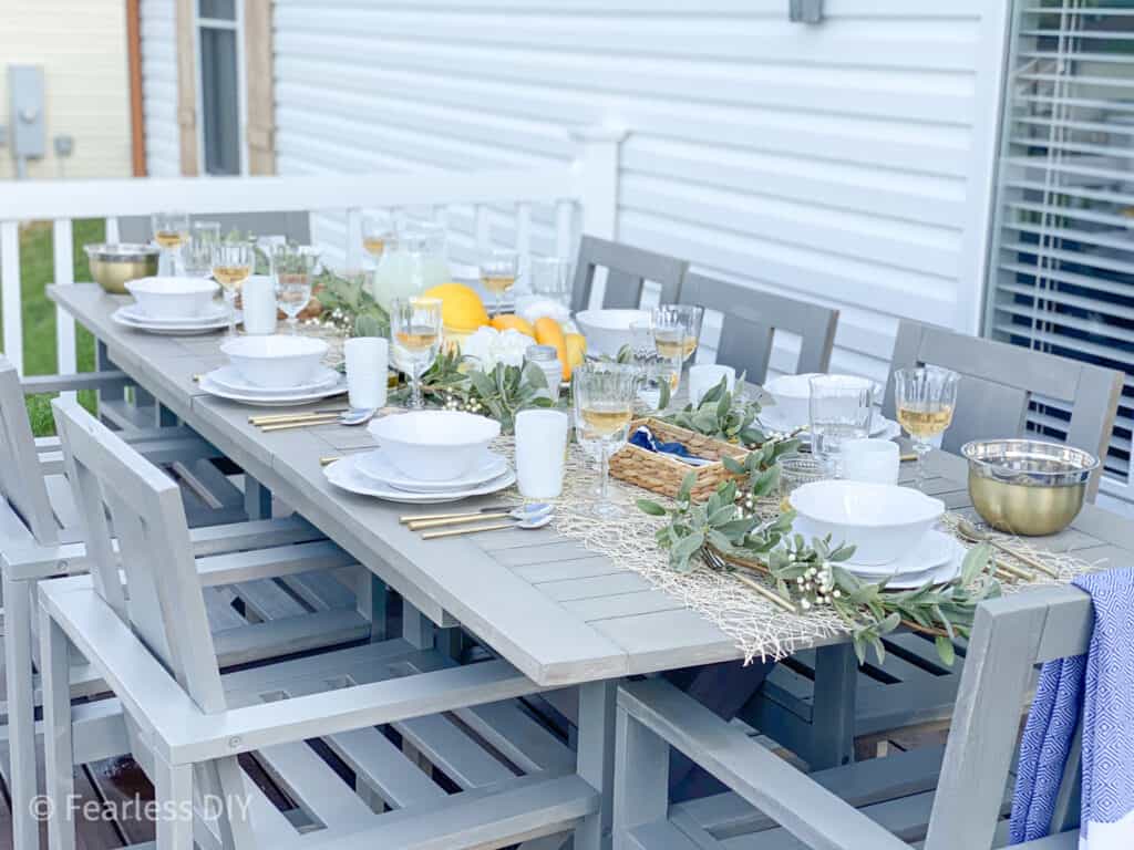 Pottery Barn Outdoor Table set with ivory dishes, crystal glassware, gold utensils with a centerpiece of lamb's ear with yellow melons, squash and candles style by fearlessdiy