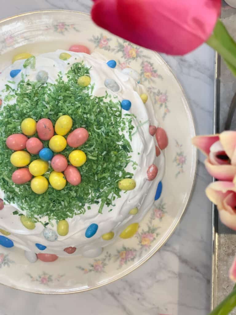 easter coconut cake decorated with robins egg candy on an antique floral plate with pink roses. 
