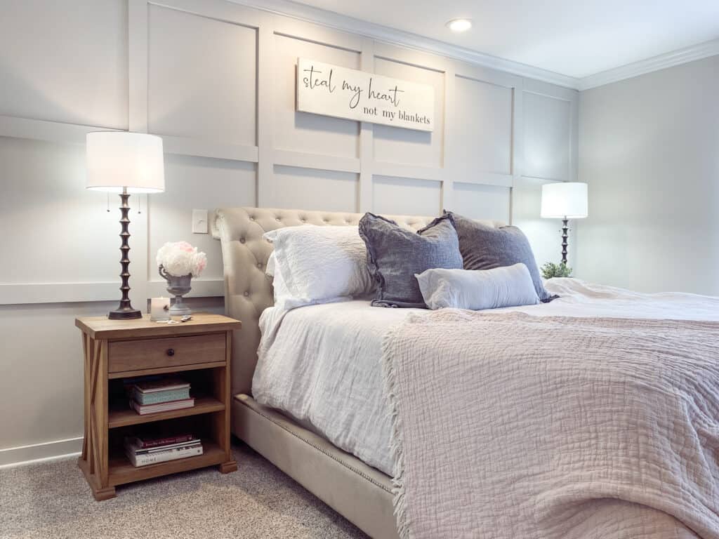 board and batten master bedroom with linen bedding, natural wood nightstand