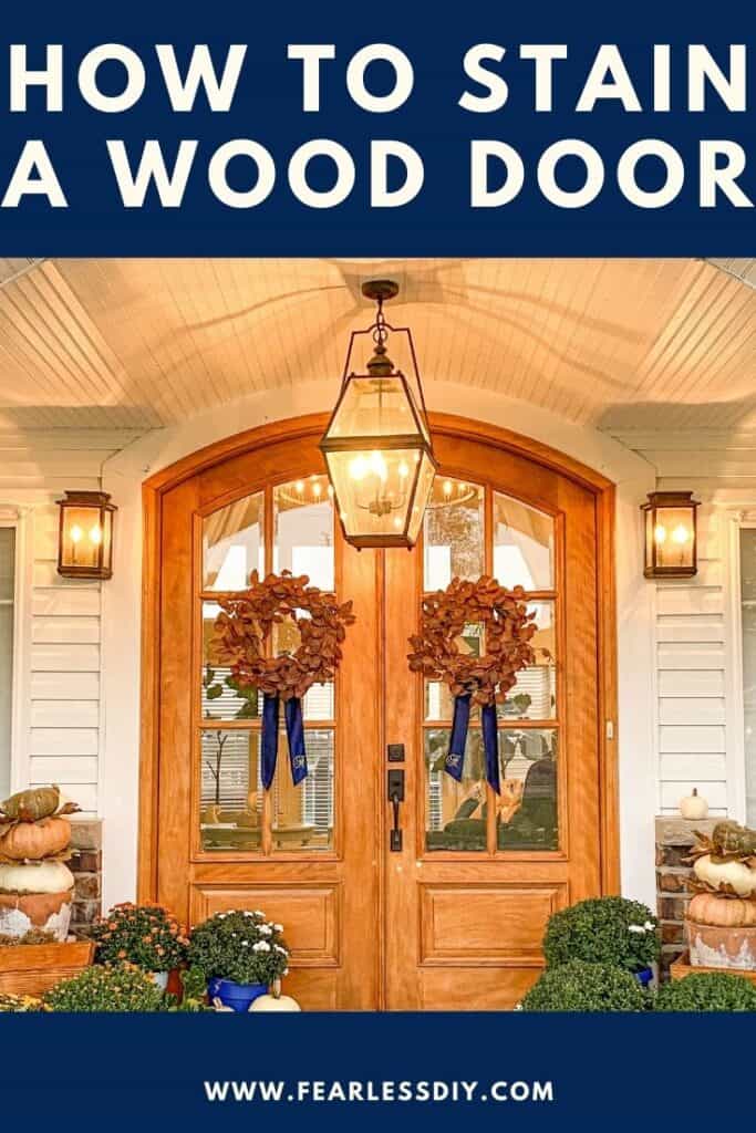 Arched wooden front doors with rust eucalyptus wreaths with blue velvet wreath sashes. 