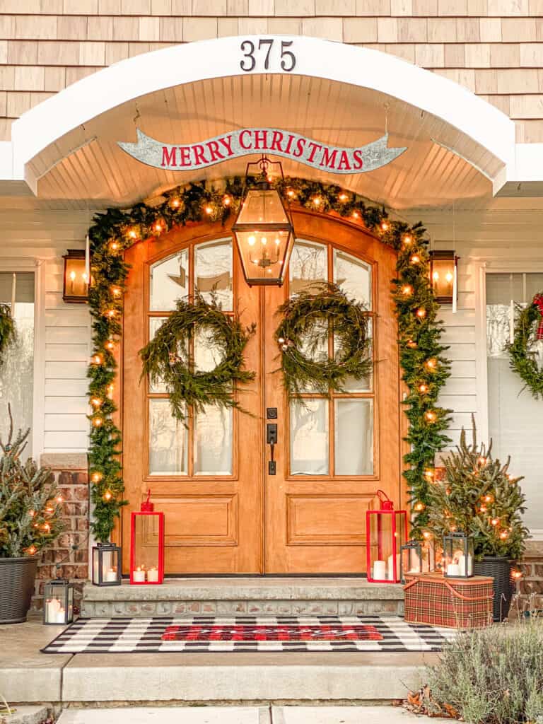 Merry Christmas sign with fresh greenery around a double front door.